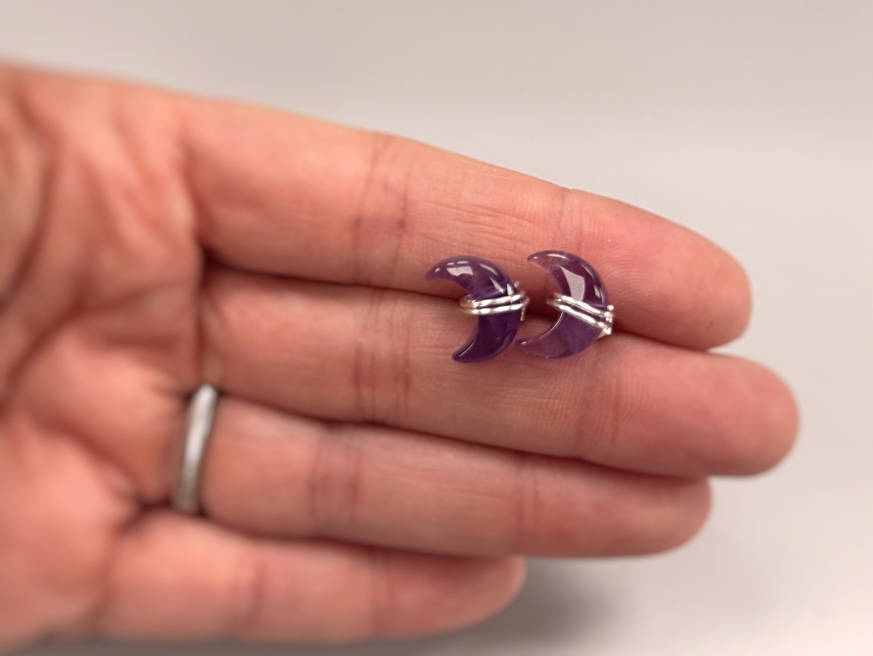 Crescent Moon Amethyst Stud Earrings in Sterling Silver in hand for scale