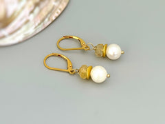 Citrine pearl earrings with gold leverback closures on gray