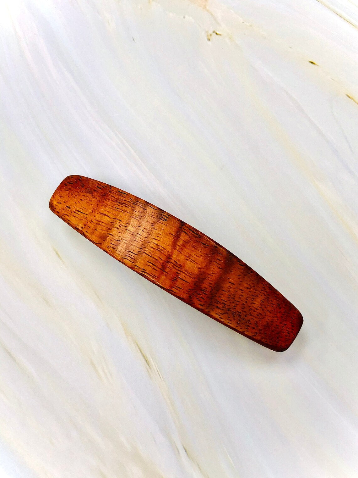 May include: A wooden hair clip with a reddish-brown color and a smooth, polished finish.