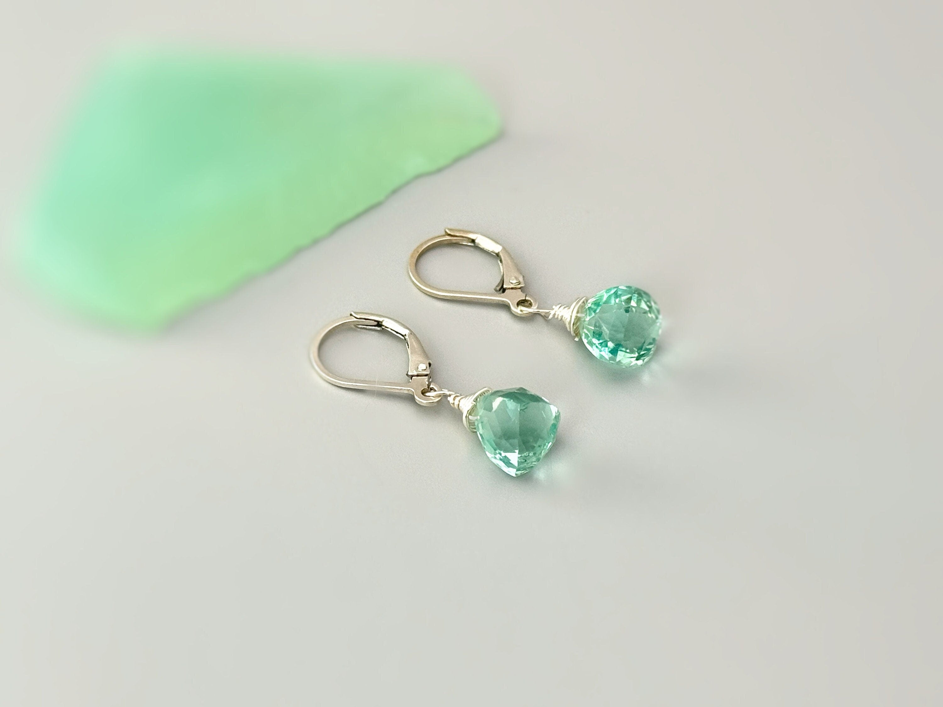 May include: A pair of silver dangle earrings with light green gemstone drops