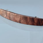 May include: A dark brown wooden hair clip with a silver metal clasp.