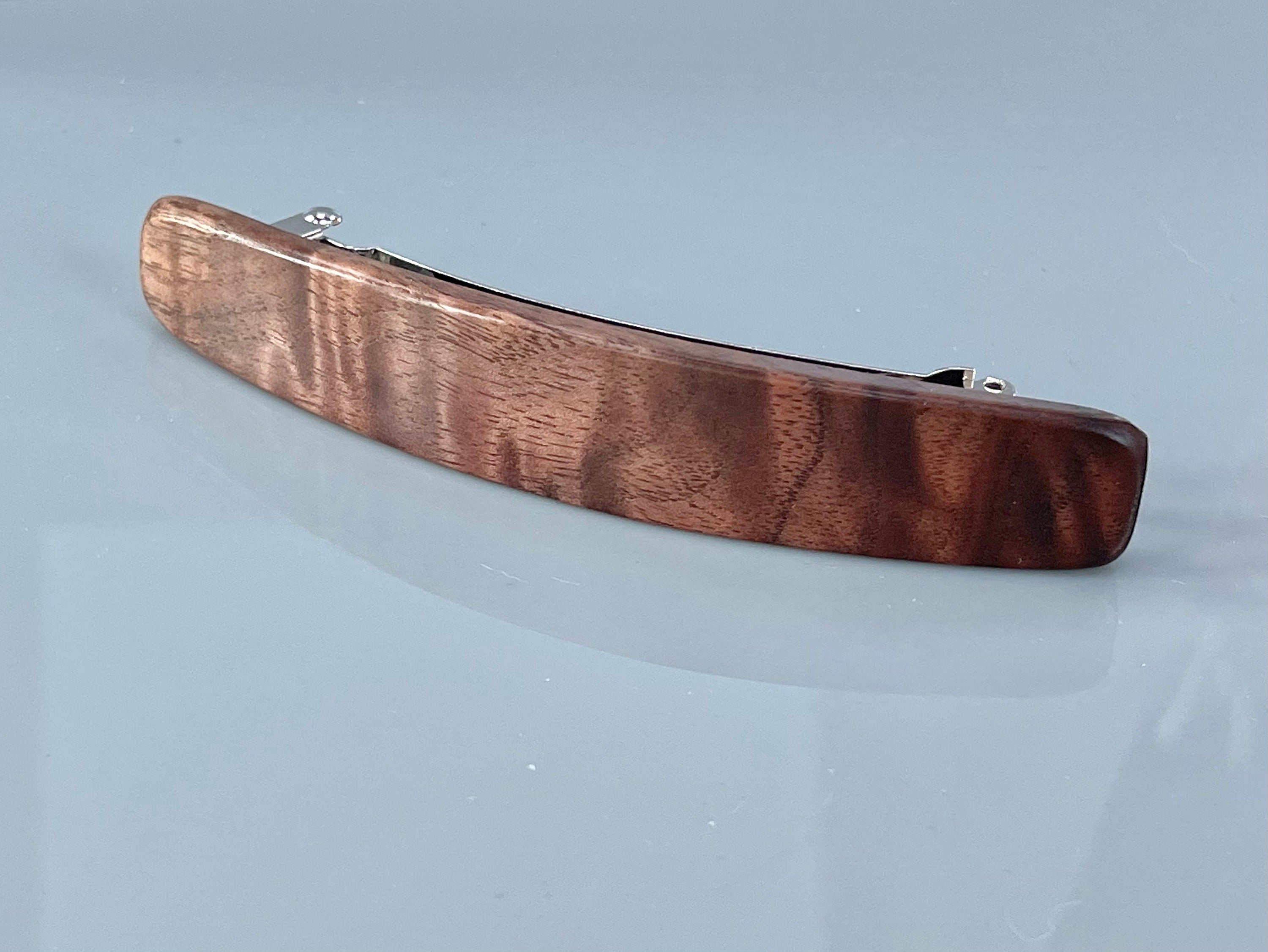 May include: A dark brown wooden hair clip with a silver metal clasp.