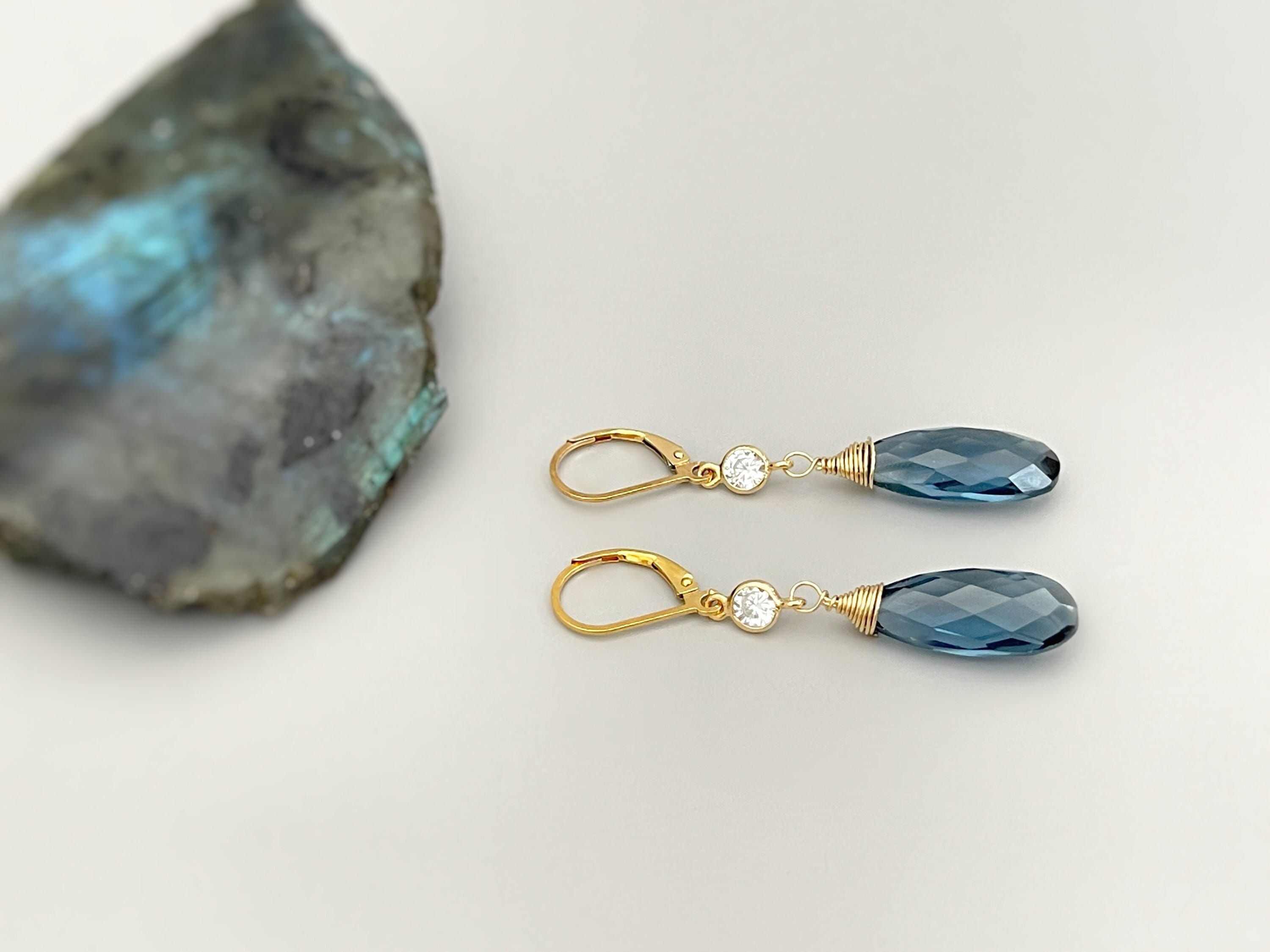 May include: Gold dangle earrings with blue teardrop shaped stones and clear round stones