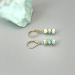 May include: A pair of gold earrings with light blue and green gemstone beads