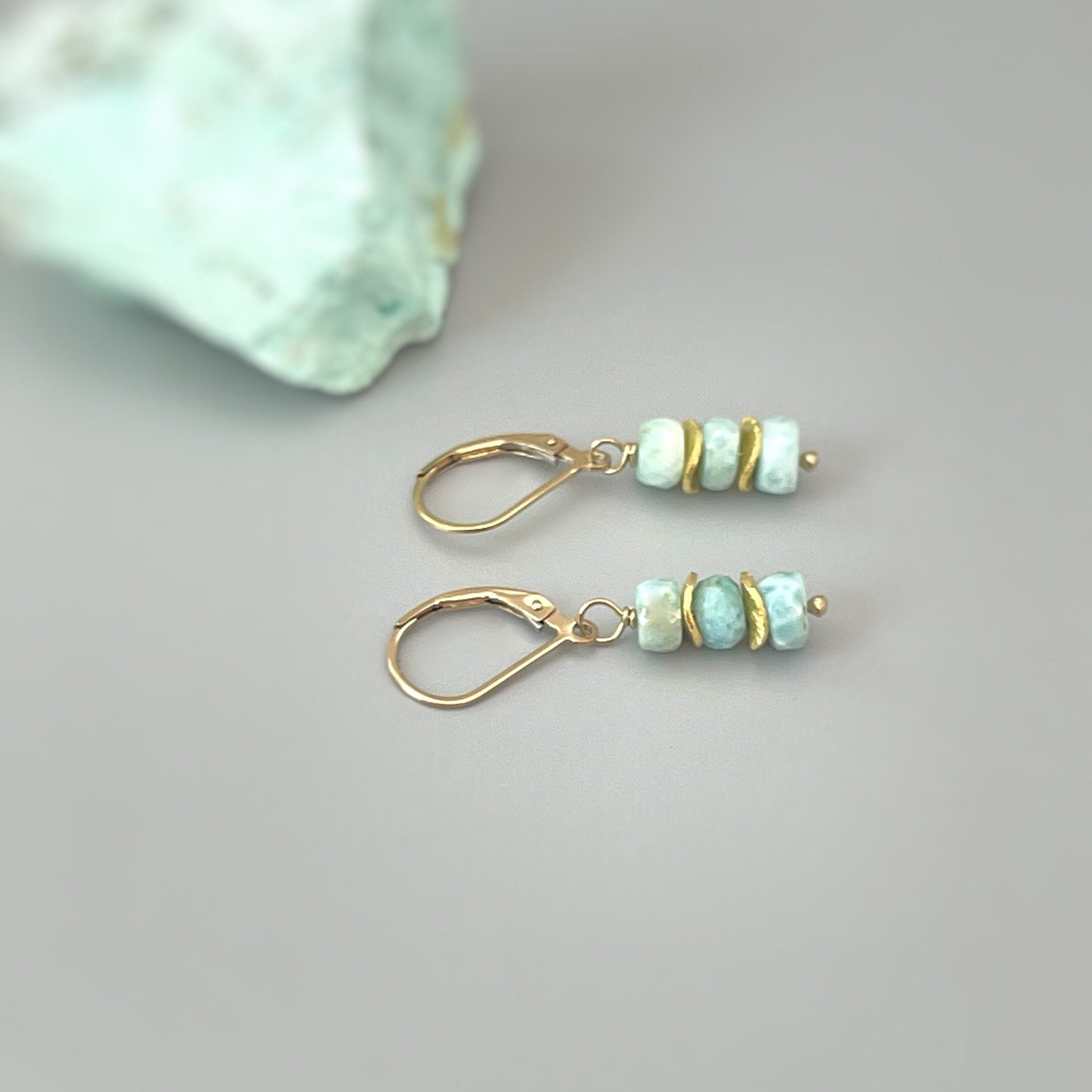May include: A pair of gold earrings with light blue and green gemstone beads