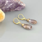 May include: A pair of gold wire wrapped earrings with teardrop shaped amethyst stones