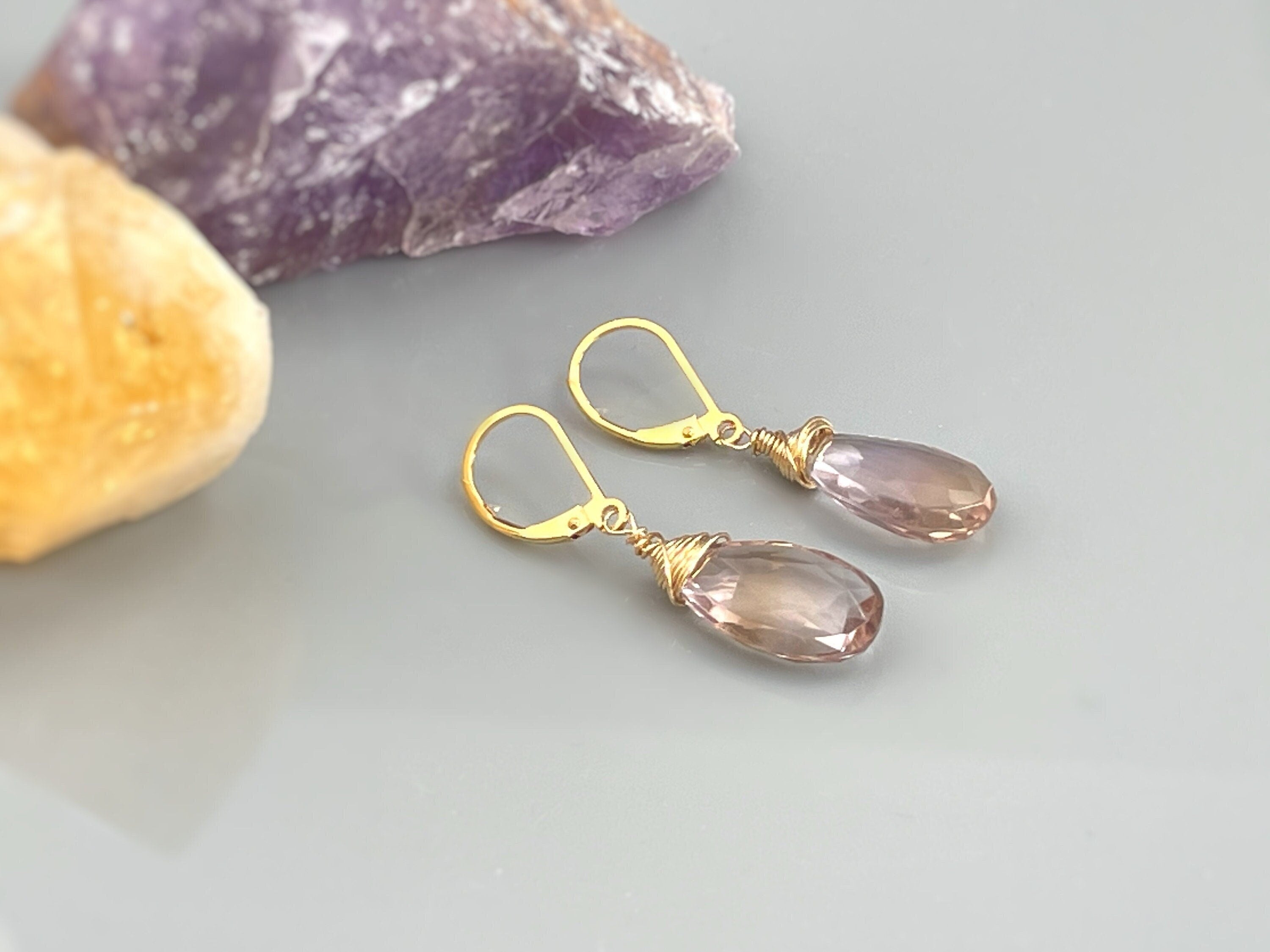 May include: A pair of gold wire wrapped earrings with teardrop shaped amethyst stones
