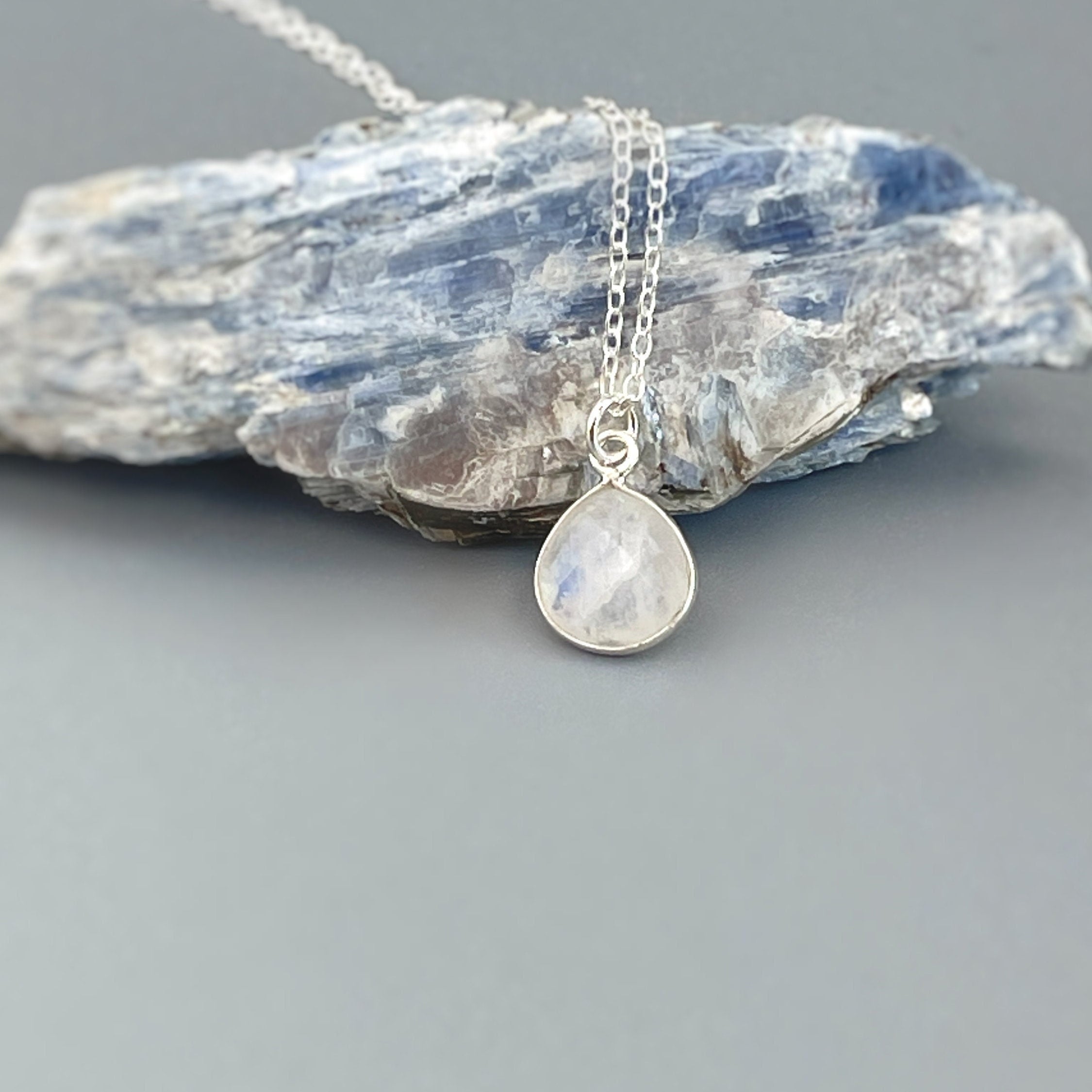 May include: A silver chain necklace with a teardrop shaped moonstone pendant