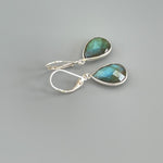 May include: A pair of silver dangle earrings with teardrop shaped green labradorite stones.
