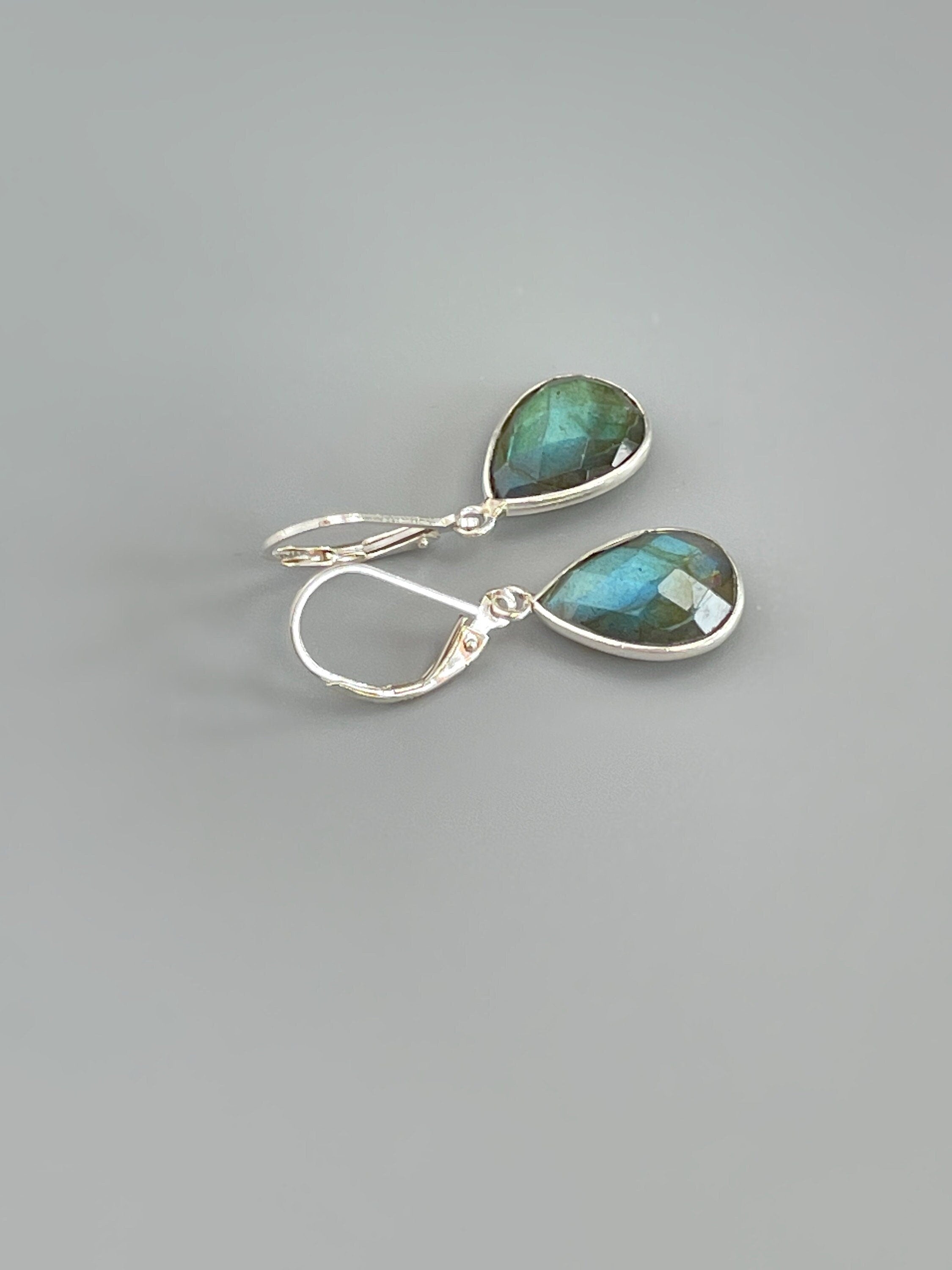 May include: A pair of silver dangle earrings with teardrop shaped green labradorite stones.