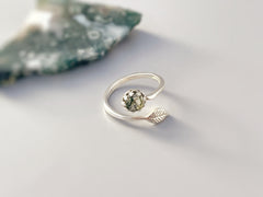 May include: A silver ring with a green stone and a leaf design.