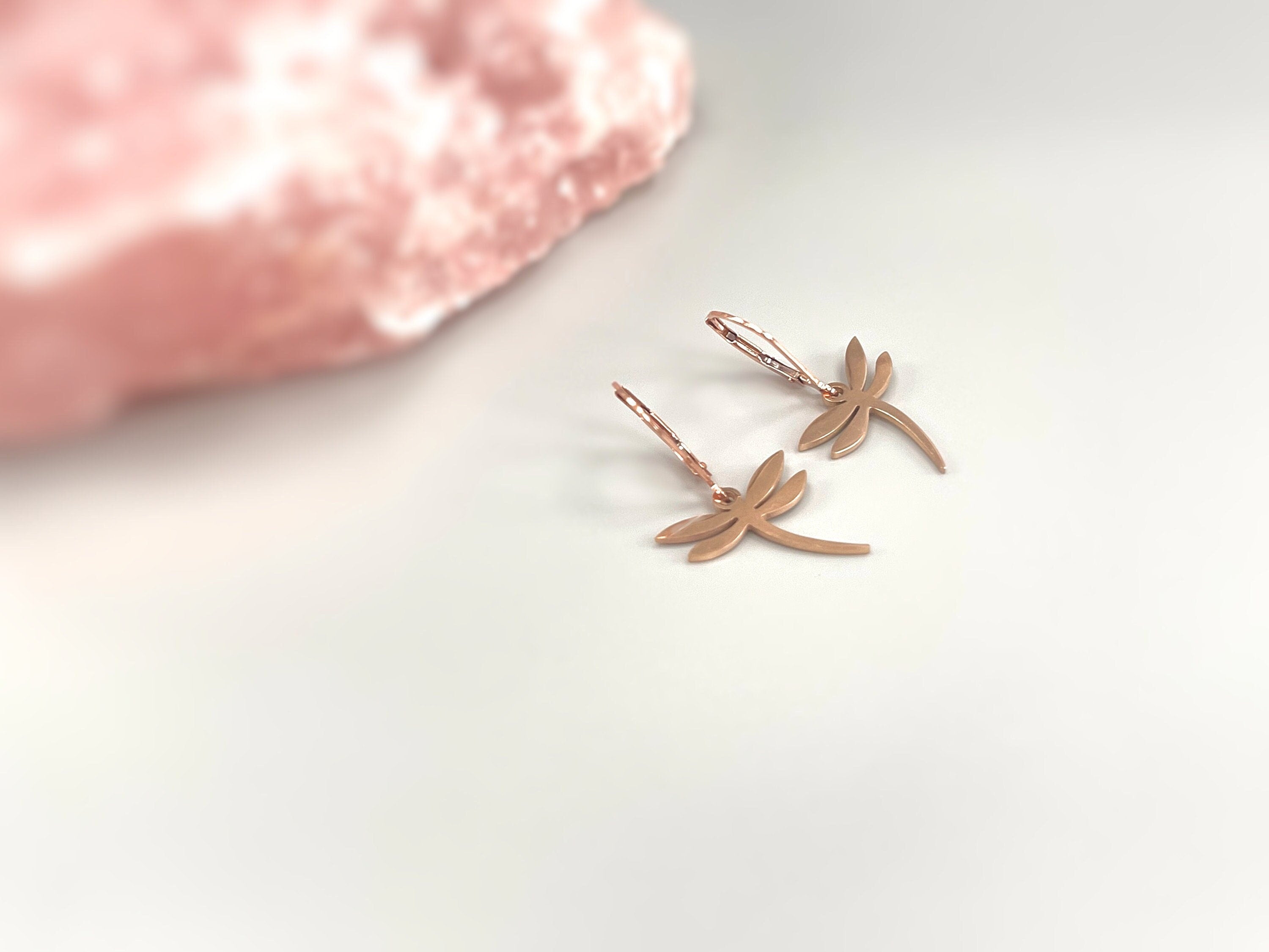 May include: Two rose gold dragonfly earrings with a hoop design