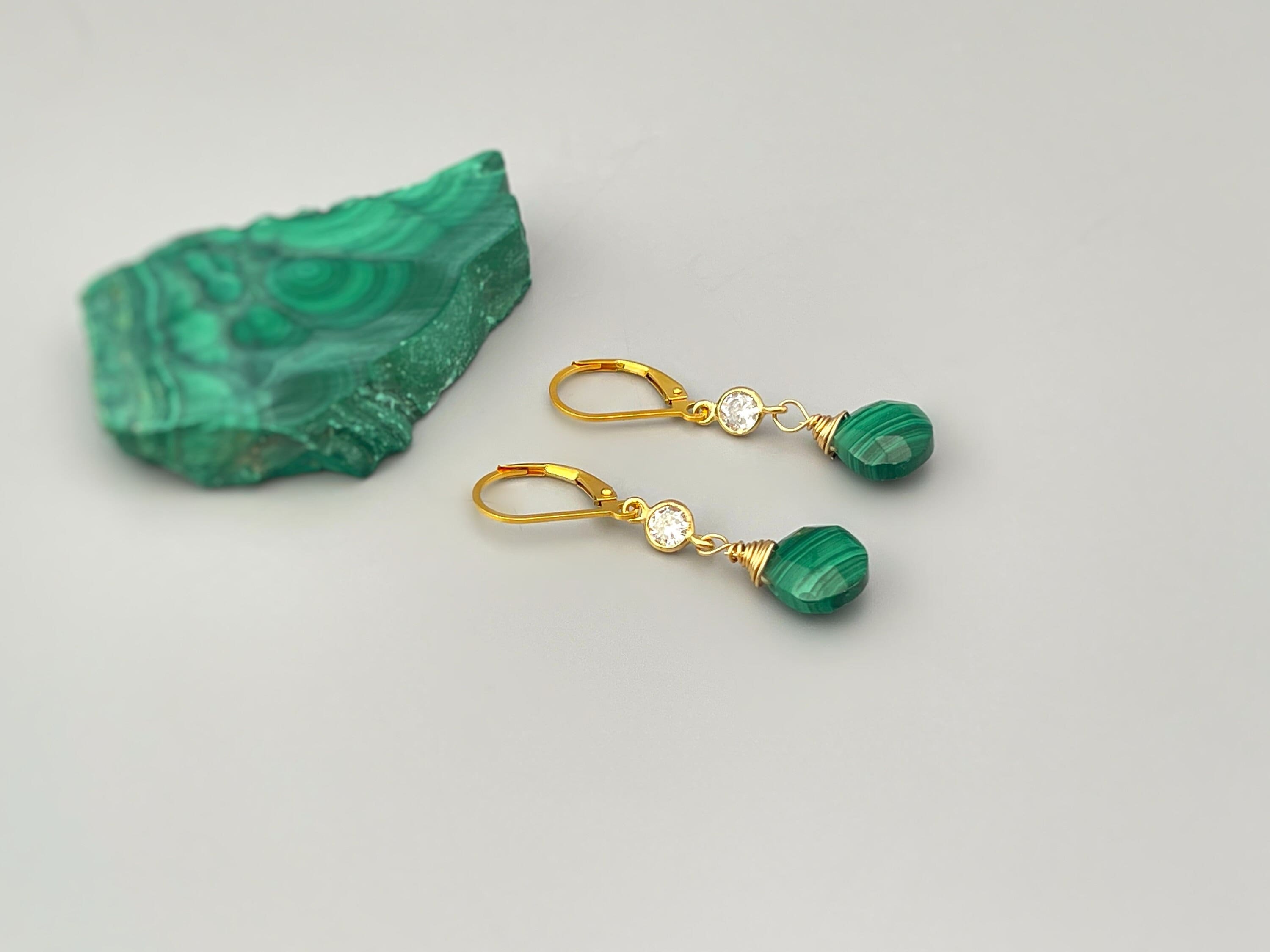 May include: Gold earrings with green malachite stones and clear cubic zirconia accents.