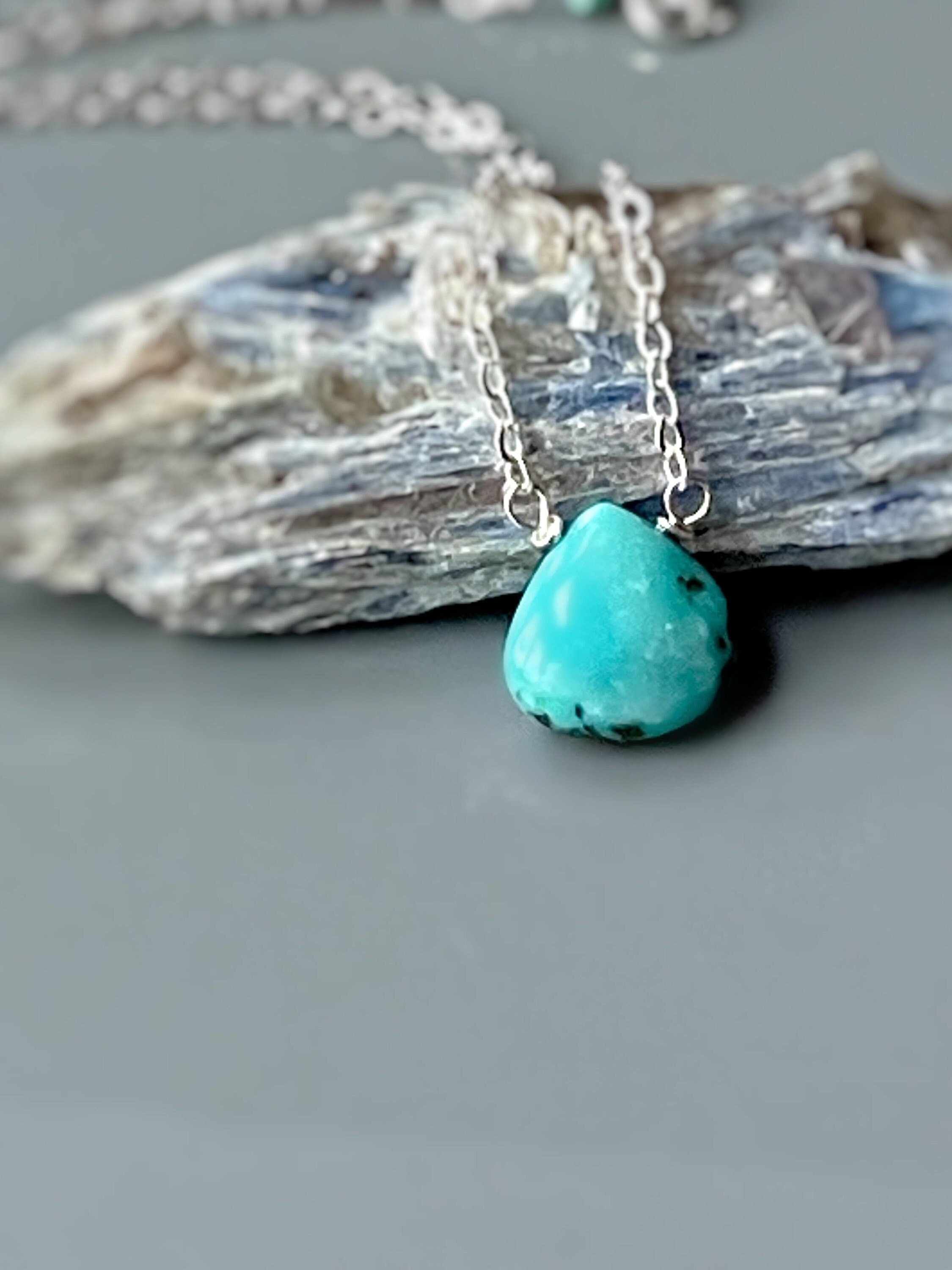 May include: A turquoise gemstone pendant necklace with a silver chain.
