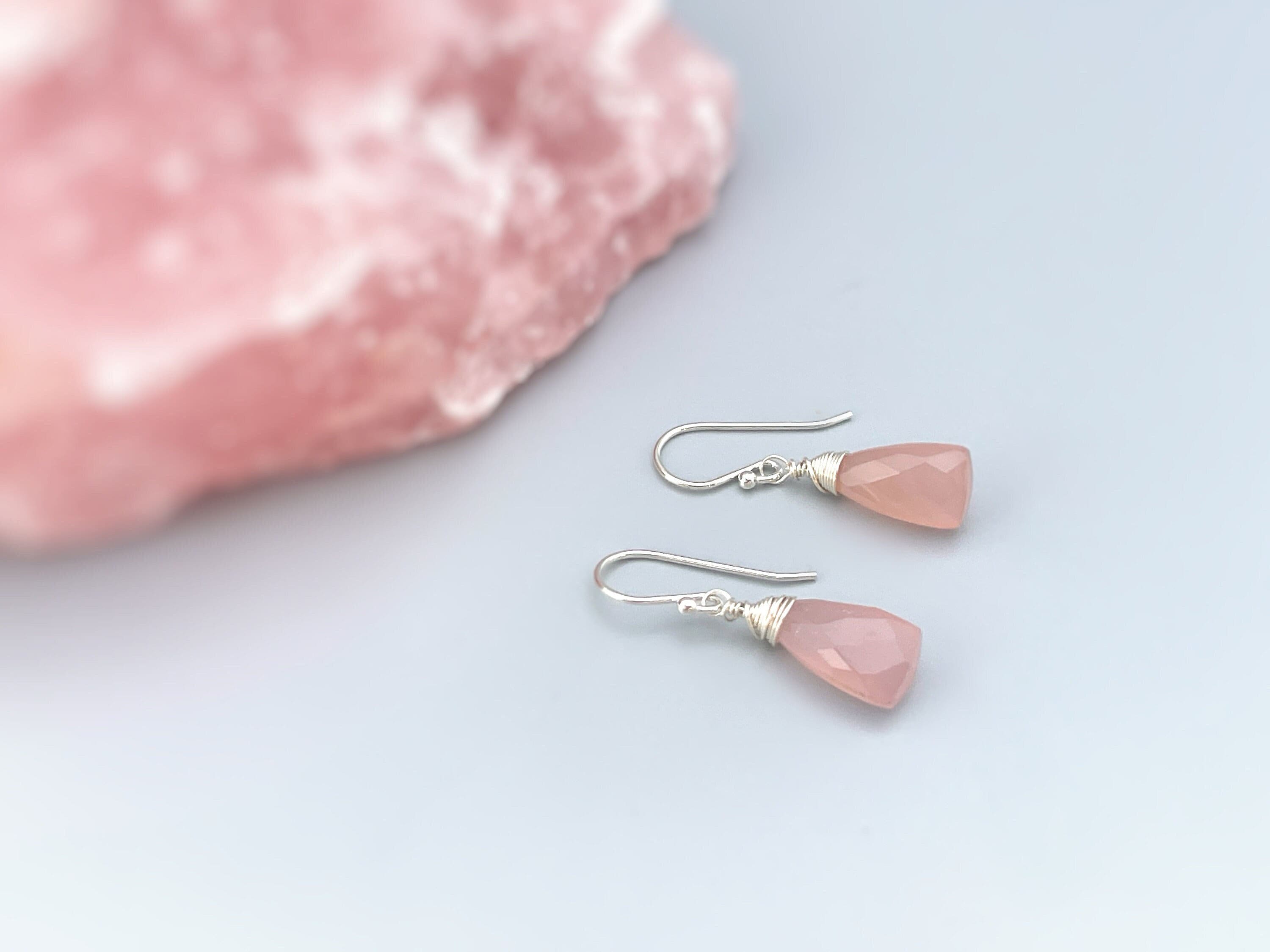 May include: A pair of silver dangle earrings with pink gemstone drops. The earrings have a simple design and are perfect for everyday wear.