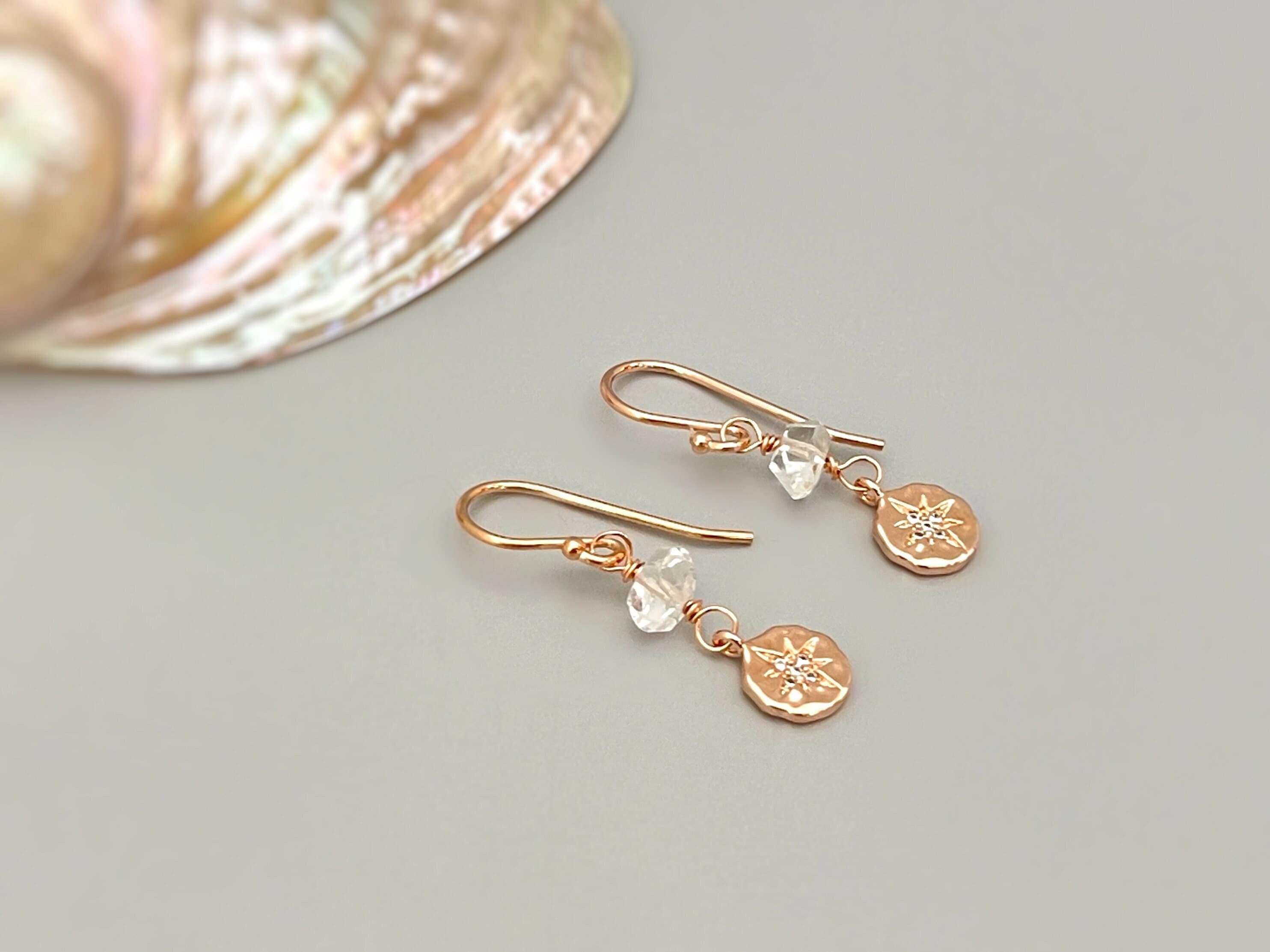 May include: A pair of gold earrings with a small clear crystal and a star-shaped charm on each earring.