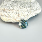 May include: A green, white, and black agate gemstone pendant on a clear string necklace.