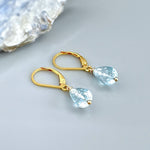 May include: A pair of gold teardrop earrings with light blue gemstone accents.