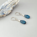 May include: A pair of silver dangle earrings with dark blue teardrop shaped gemstones