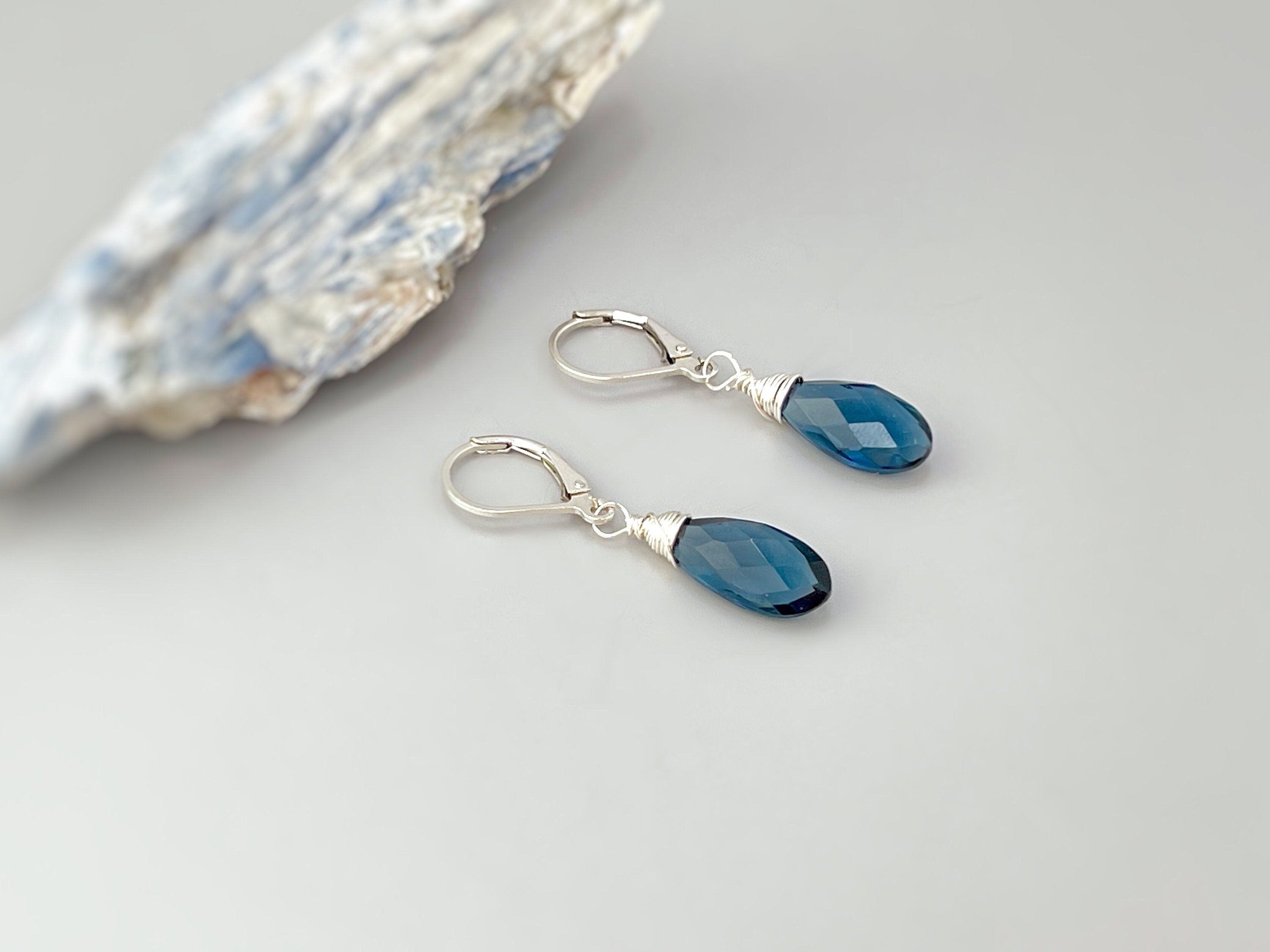 May include: A pair of silver dangle earrings with dark blue teardrop shaped gemstones