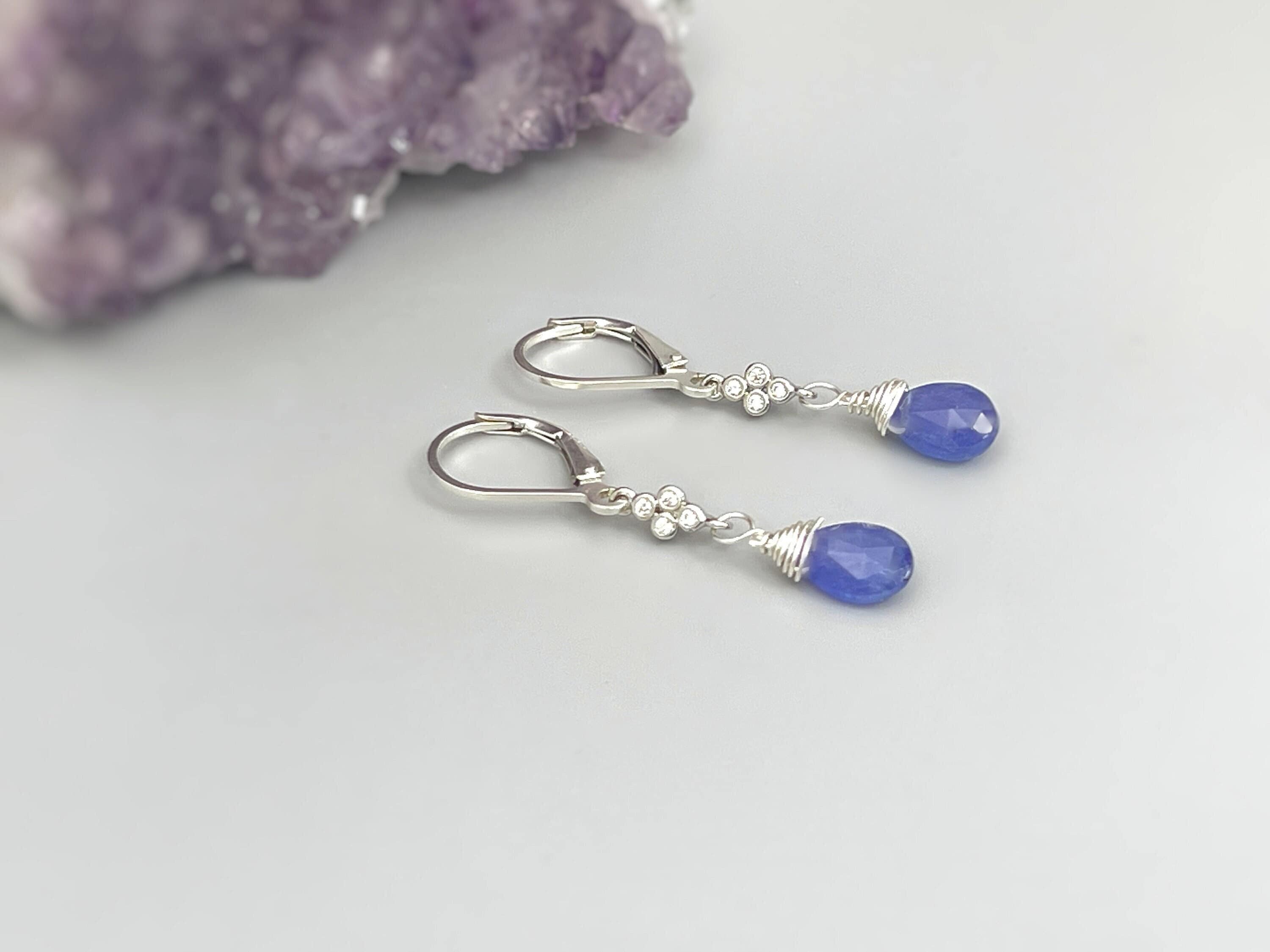 May include: A pair of silver dangle earrings with blue teardrop shaped stones and small silver flower accents