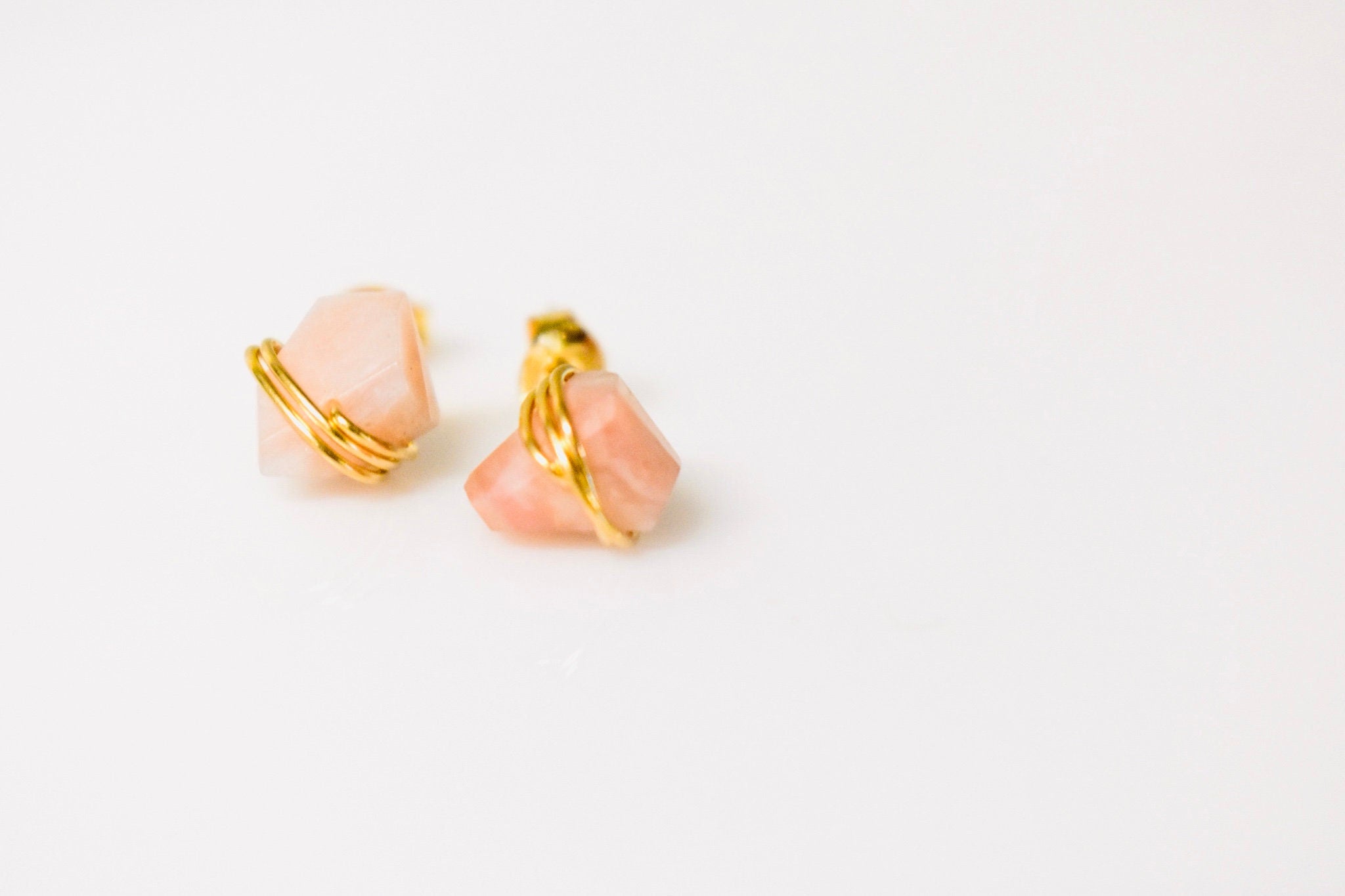 May include: Two gold wire wrapped pink gemstone earrings