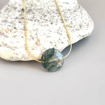 May include: A gold chain necklace with a green and white agate pendant