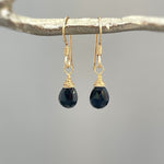 May include: Gold dangle earrings with black faceted teardrop gemstones