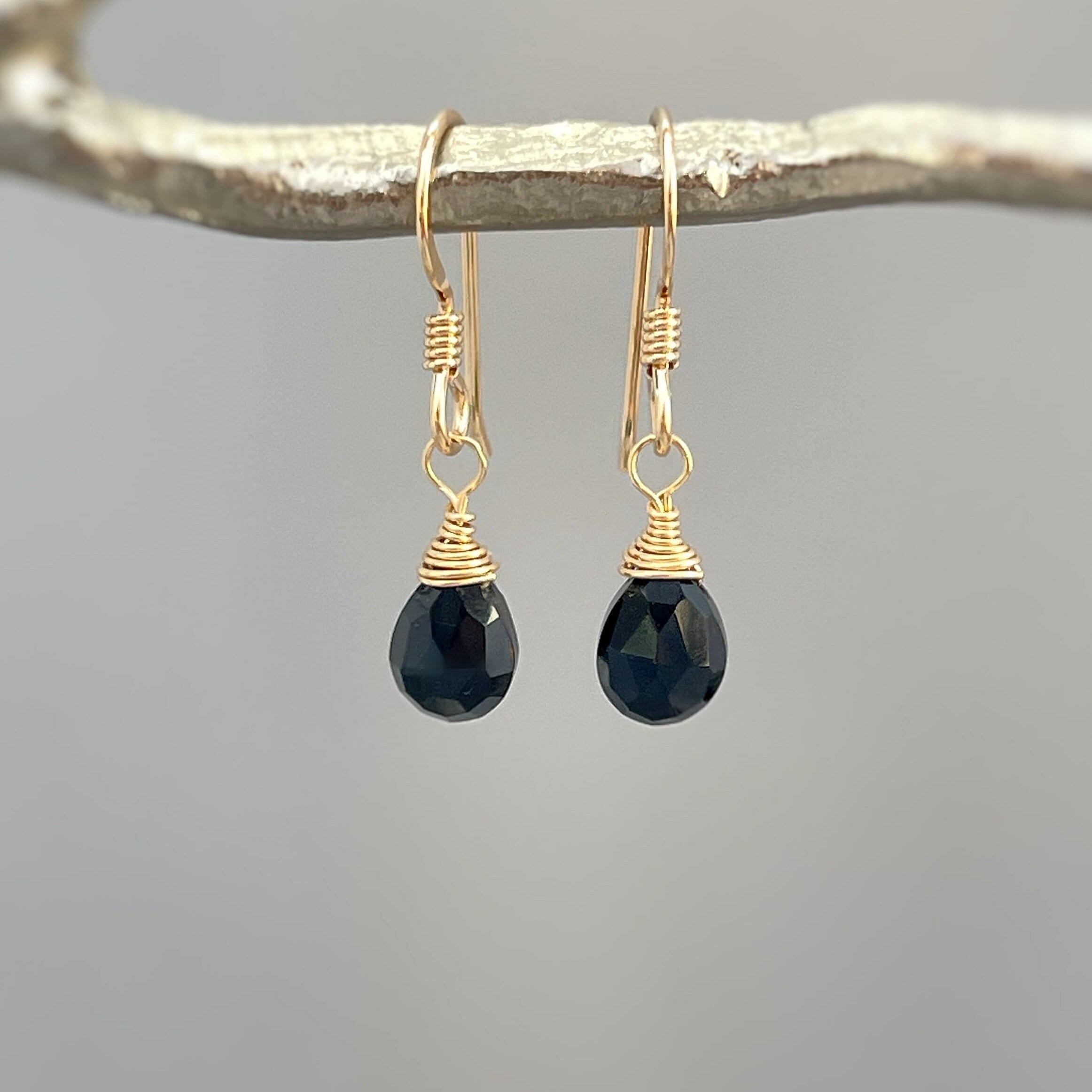 May include: Gold dangle earrings with black faceted teardrop gemstones
