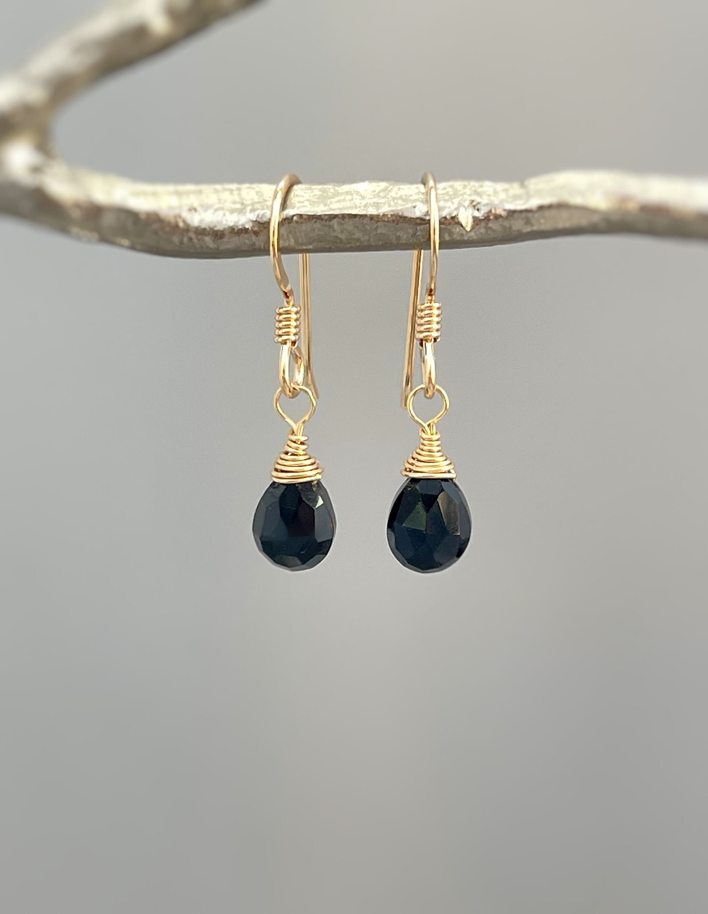 May include: Gold dangle earrings with black faceted teardrop gemstones