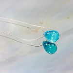 May include: A silver chain necklace with a teardrop shaped light blue pendant