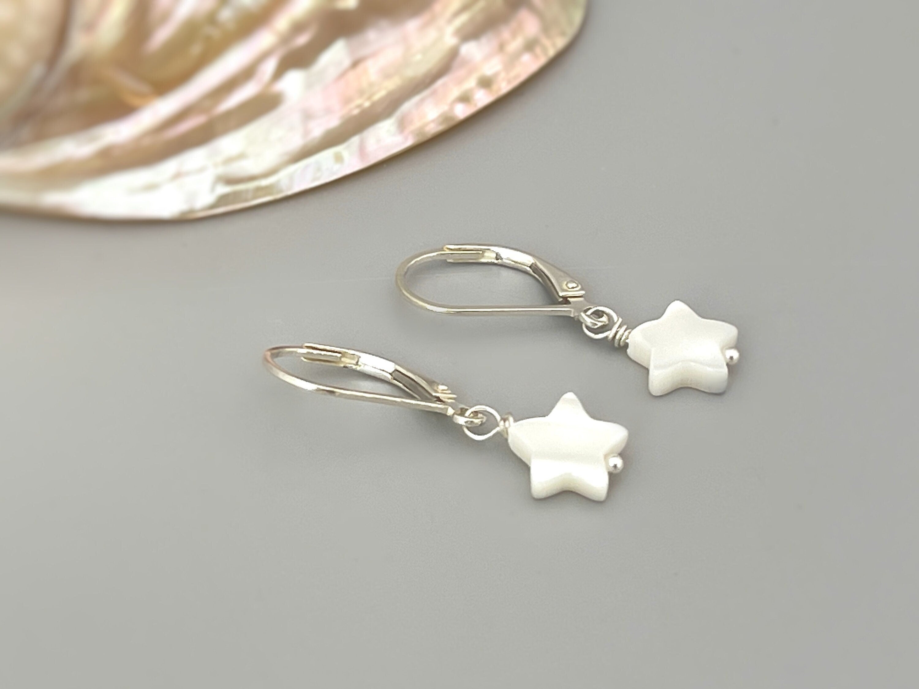 May include: A pair of silver dangle earrings with white star-shaped charms