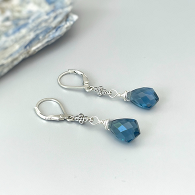 a pair of blue crystal earrings sitting on top of a table