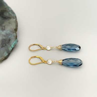 a pair of blue crystal earrings sitting on top of a rock