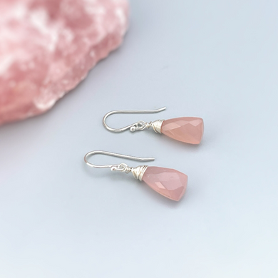 a pair of pink earrings sitting on top of a pink rock