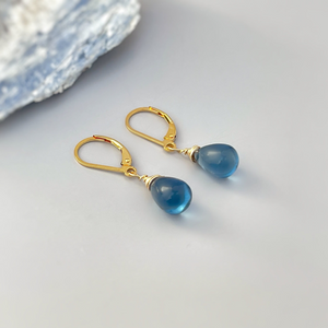 a pair of gold earrings with blue glass drops
