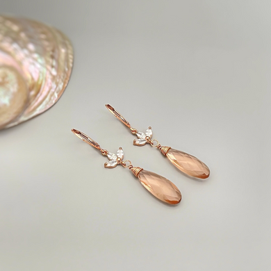 a pair of earrings sitting next to a seashell