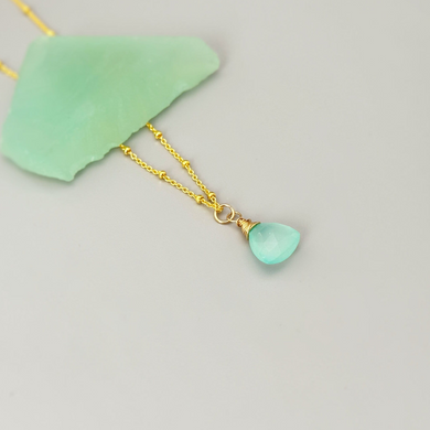 a gold necklace with a green stone hanging from it