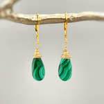 a pair of green and gold earrings on a branch