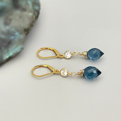 a pair of gold - plated earrings with blue crystal drops