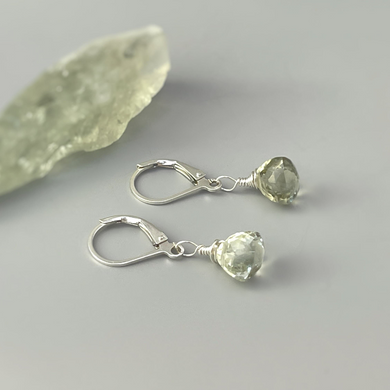 a pair of earrings sitting next to a piece of rock