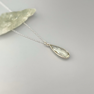 a silver necklace with a tear shaped pendant