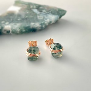 a pair of earrings sitting on top of a rock