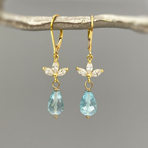 a pair of gold earrings with blue topazte and diamonds