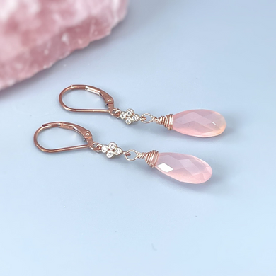 a pair of pink earrings sitting on top of a pink rock